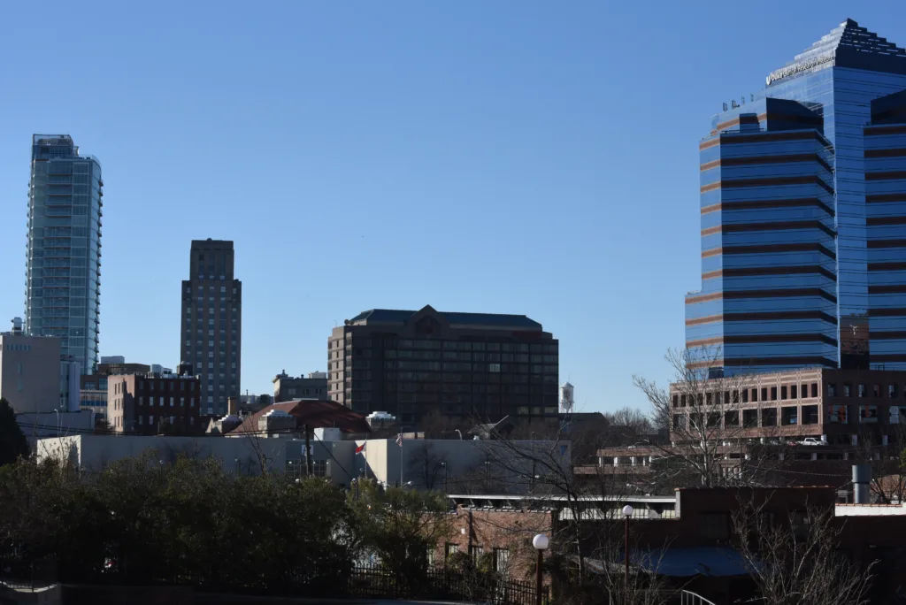 City skyline with modern and historic buildings under a clear blue sky.